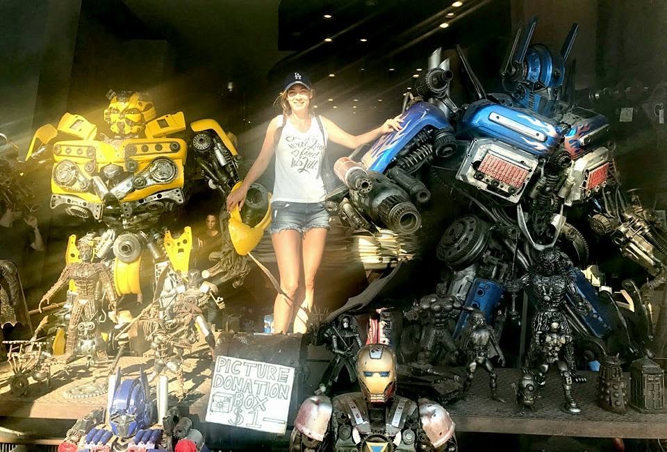 Žaneta standing among robot sculptures built from scrap metal